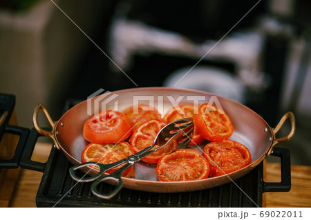 Close-up of sliced fried tomatoes in a frying pan on a cast iron stove. 69022011