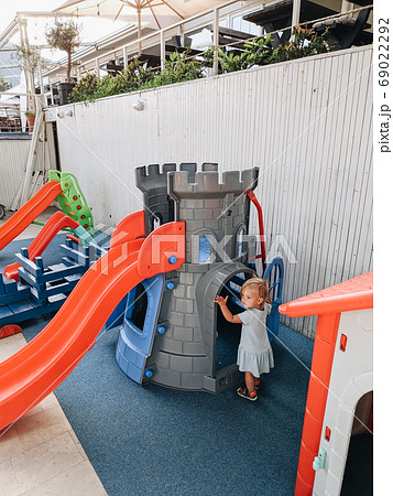 A little girl plays on the playground near a plastic castle and a children's slide. 69022292