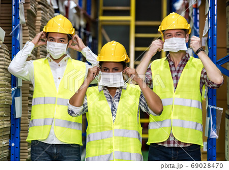 Interracial warehouse worker team putting on  face 69028470