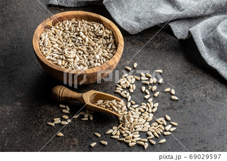 Peeled sunflower seeds in wooden bowl and wooden scoop. 69029597