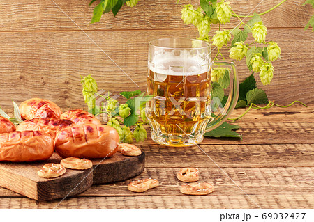 Fried sausages on wooden chopping board and glass of beer on wooden background 69032427