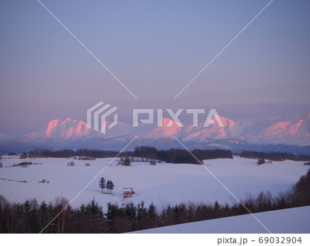 夕映えの大雪山系と赤い屋根の家 69032904