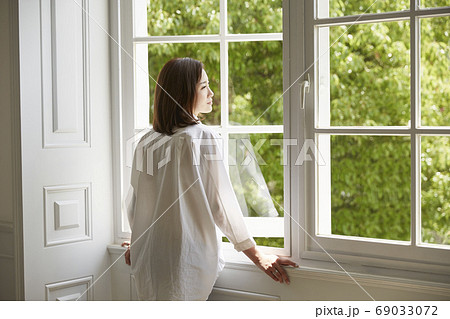 young asian woman staying at home looking out of 69033072