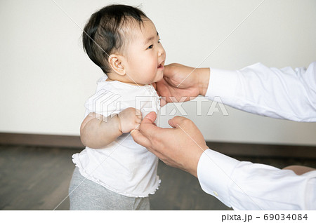 部屋でつかまり立ちする元気な赤ちゃんの写真素材