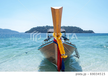 Long tail boat sailing through the blue sea with blue sky background Long tail boat sailing through the blue sea with blue sky background 69034515
