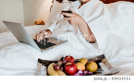 Picture of tourists used laptop and eating fruits on the bed, health food concept Picture of tourists used laptop and eating fruits on the bed, health food concept 69034531