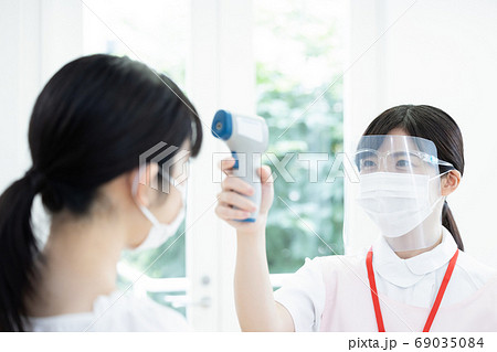 医療 フェイスシールドを付けて検温をする看護師 医療 フェイスシールドを付けて検温をする看護師 69035084