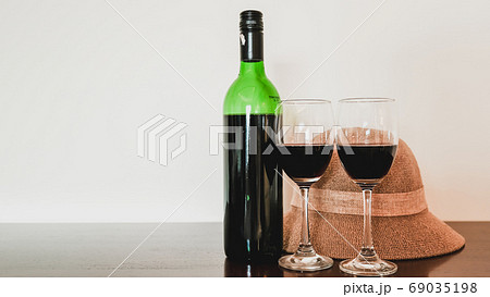 Two glasses of wine and wine bottle with hat on the wooden table 69035198