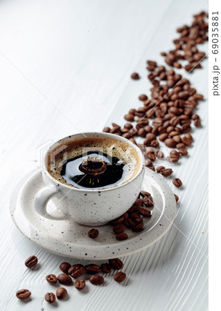 Black coffee and coffee beans on a white table. Black coffee and coffee beans on a white table. 69035881