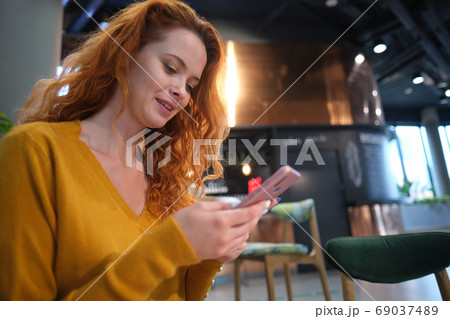 Portrait of smiling young woman sitting in cafe at center mall a 69037489