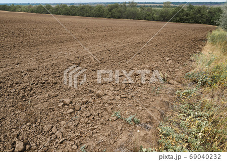 plowed field and blue sky, soil and clouds of a bright sunny day - concept of agriculture 69040232