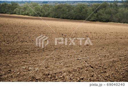 plowed field and blue sky, soil and clouds of a bright sunny day - concept of agriculture plowed field and blue sky, soil and clouds of a bright sunny day - concept of agriculture 69040240