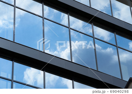 facade of a modern building on a bright Sunny day, blue sky and clouds reflecting in a glass, beautiful exterior of the new building 69040298