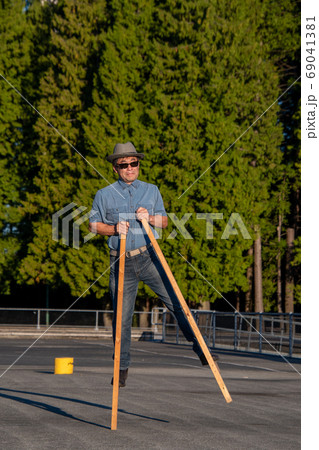 サングラスをかけた中年男性が竹馬の片方に乗る様子　　バンクーバー　ブリティッシュコロンビア　カナダ 69041381