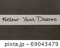 White and Grey coloured paper background with Follow Your Dreams motivational handwritten message 69043479