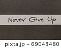 White and Grey coloured paper background with Never Give Up motivational handwritten message 69043480