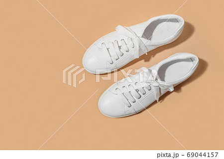 White female gumshoes on beige background. White female gumshoes on beige background. 69044157