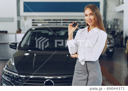 Young happy woman buyer/seller near the car with keys in hand 69044371