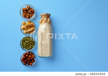 Vegetable milk concept with milk bottle and bowls with grains on blue background top view 69044409