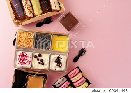 Carton boxes with eclair cakes and cookies on pink surface Carton boxes with eclair cakes and cookies on pink surface 69044443