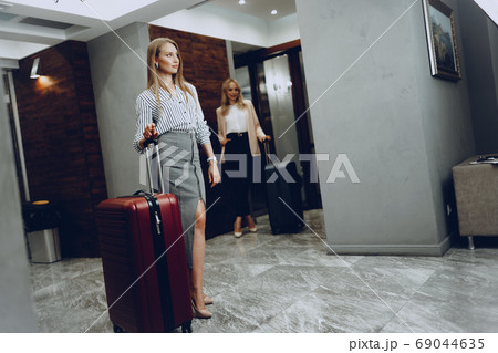 Two young women in formal clothes entering hotel lobby 69044635