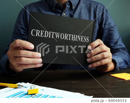 The man shows an sign Creditworthiness on a black page. The man shows an sign Creditworthiness on a black page. 69049353