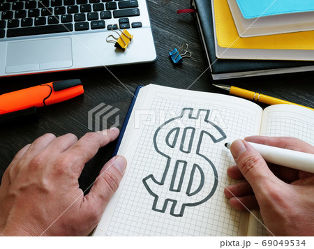 Hands are drawing a dollar sign in a notebook. Personal finance and wealth management. Hands are drawing a dollar sign in a notebook. Personal finance and wealth management. 69049534