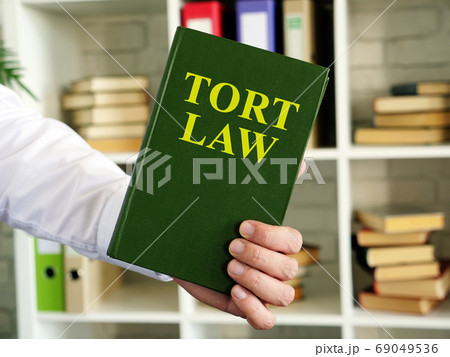Hand shows a Tort law book in the office. 69049536