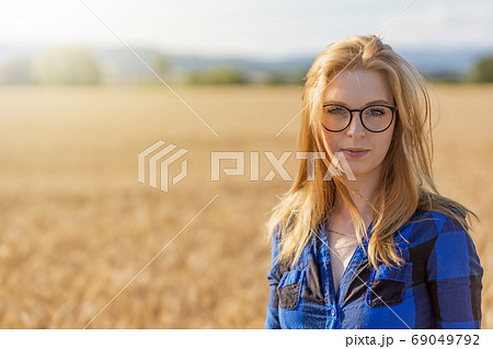 Young woman is posing in corn field looking at the camera. 69049792