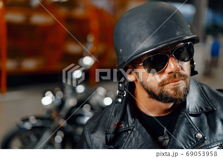 Portrait of bearded man motocyclist in dark sunglasses on dark background Portrait of bearded man motocyclist in dark sunglasses on dark background 69053958