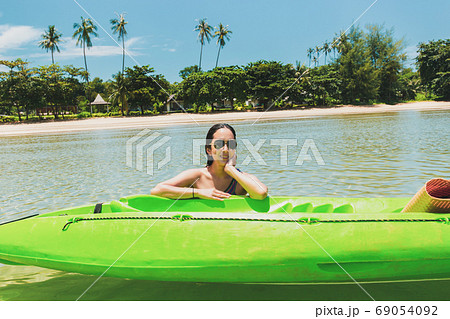 Woman with sunglass sitting in the sea with green kayak on summer vacation. Woman with sunglass sitting in the sea with green kayak on summer vacation. 69054092