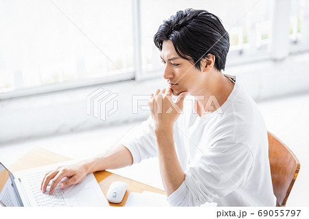 真剣な眼差しでパソコンの画面を見る若い男性の写真素材