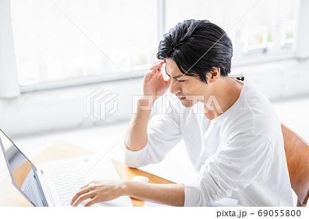 真剣な眼差しでパソコンの画面を見る若い男性の写真素材