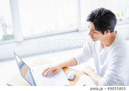 真剣な眼差しでパソコンの画面を見る若い男性 69055803