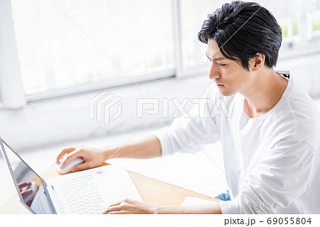 真剣な眼差しでパソコンの画面を見る若い男性 69055804