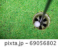 the golf ball in the golf hole. 69056802
