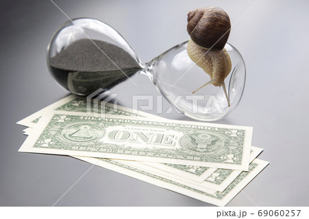 snail crawls on an hourglass against the background of money. sp snail crawls on an hourglass against the background of money. sp 69060257