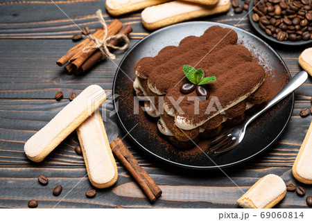 Classic tiramisu dessert on ceramic plate and savoiardi cookies on wooden background 69060814