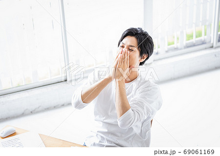 デスクワーク中に両手で顔をおさえる若い男性 デスクワーク中に両手で顔をおさえる若い男性 69061169