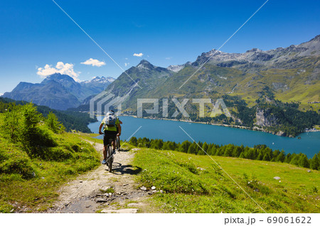 Cycling in the mountains passing through a lake Cycling in the mountains passing through a lake 69061622