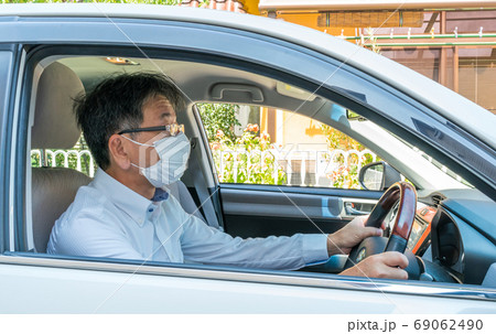 マスクをした中年男性が車を運転している 69062490