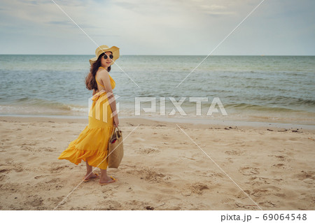 woman in yellow dress standing on sea beach with wind blow 69064548