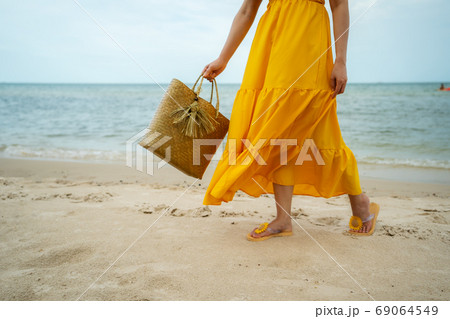 woman feet in yellow dress walking on sea beach with bag woman feet in yellow dress walking on sea beach with bag 69064549