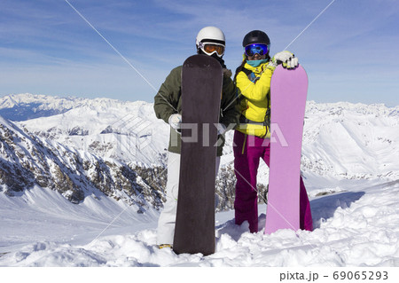 Two young happy friends snowboarders are having fun on ski slope with snowboards in sunny day. 69065293