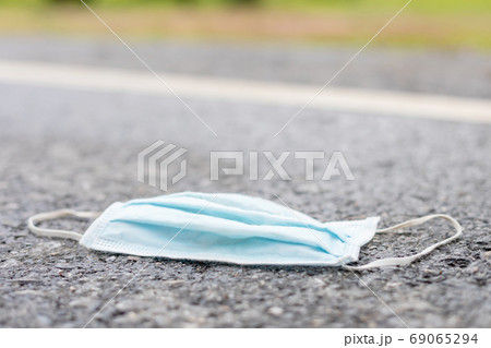 Old protective mask is on the road. After used and garbage conce 69065294