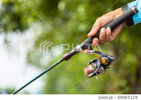 Fishing reel and rod in fisherman hand in a pond 69065329