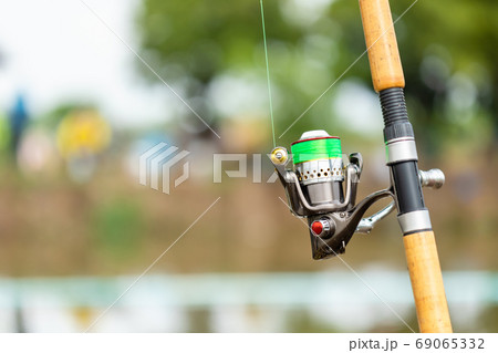 Fishing reel and rod in fisherman hand in a pond 69065332