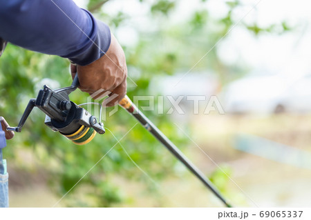 Fishing reel and rod in fisherman hand in a pond 69065337