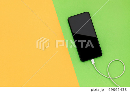 New smartphone with white charger on color background with copy New smartphone with white charger on color background with copy 69065438