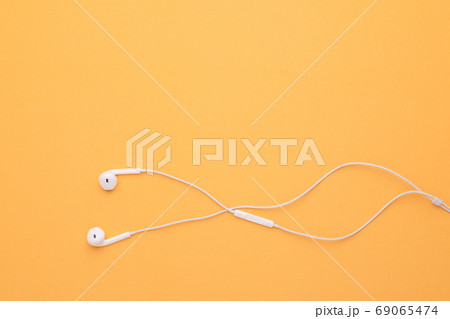 White earphone on yellow background. Copy space for text or desi 69065474